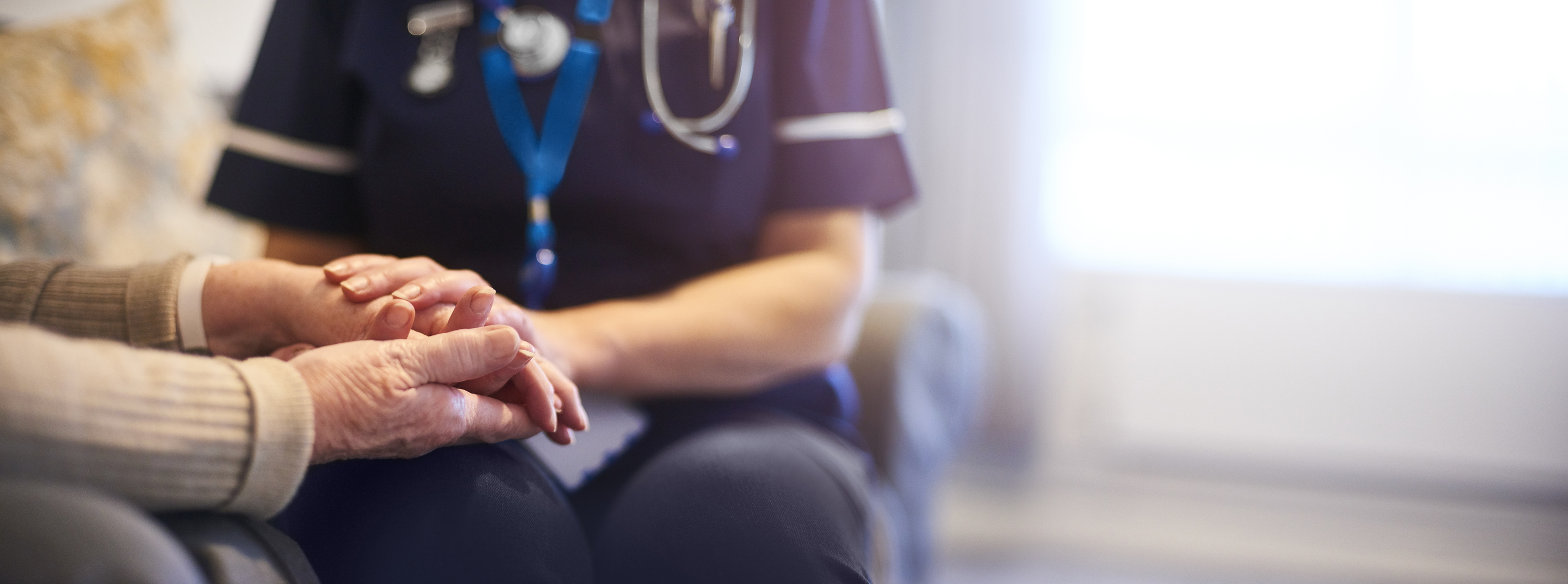 Home health nurse holding patient's hands
