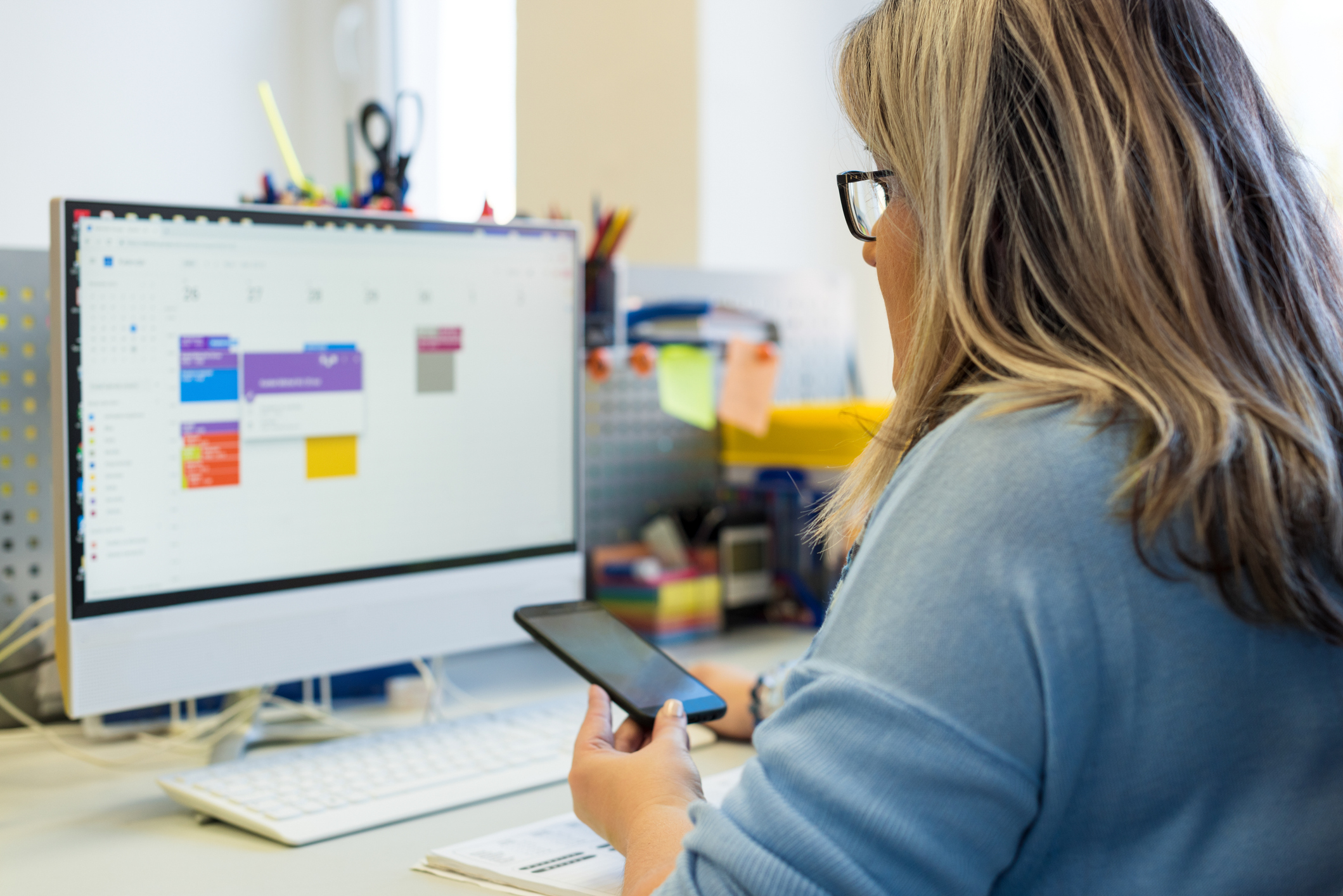 Home health scheduling coordinator at desk with calendar